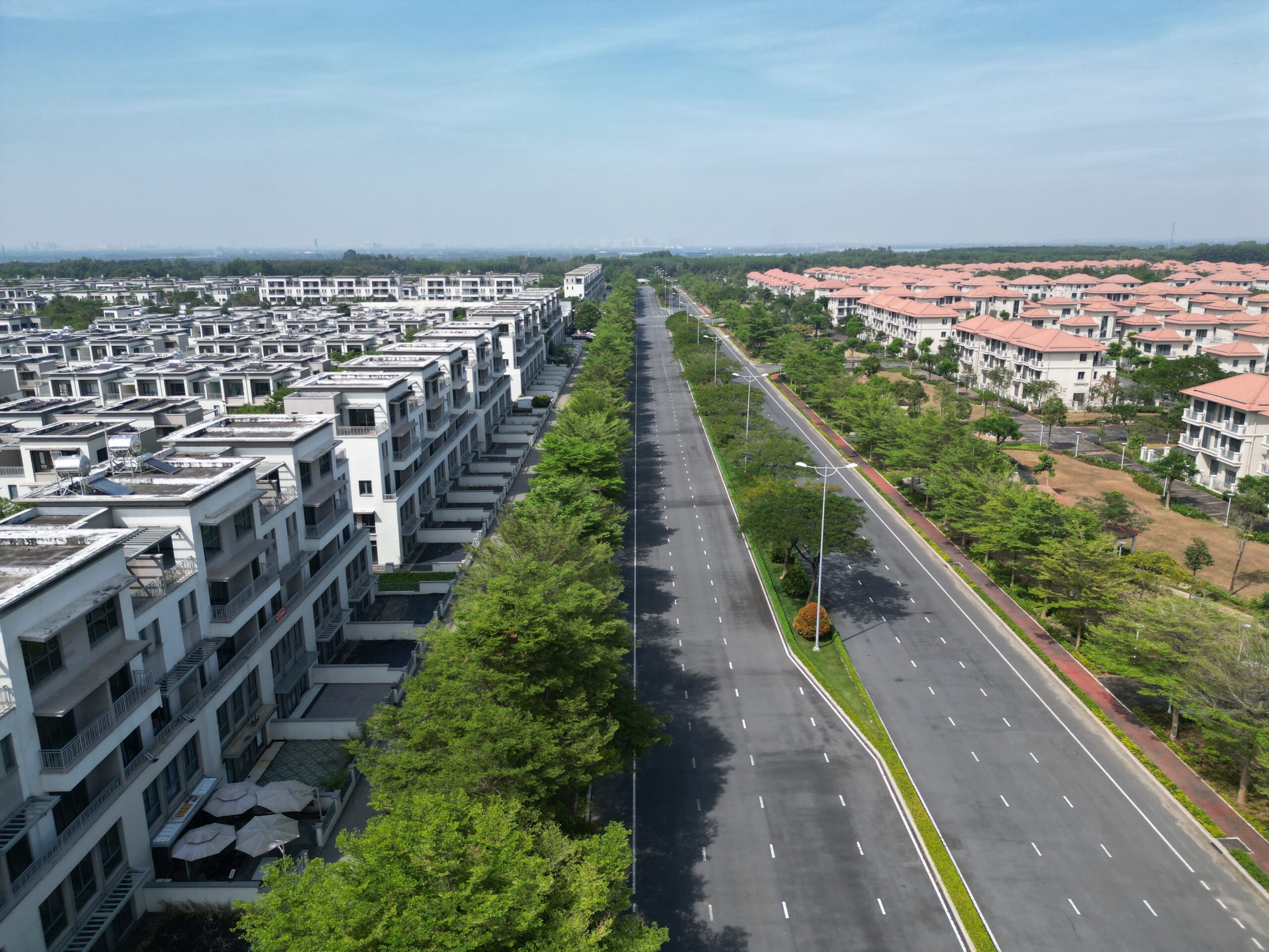 Aerial shot of a modern housing estate in Dong Nai, Vietnam, showcasing luxury homes and a wide road.